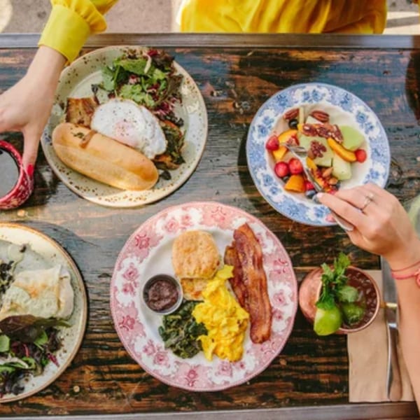 Overhead view of a rustic table laden with various breakfast dishes and drinks at Paper or Plastik Cafe.