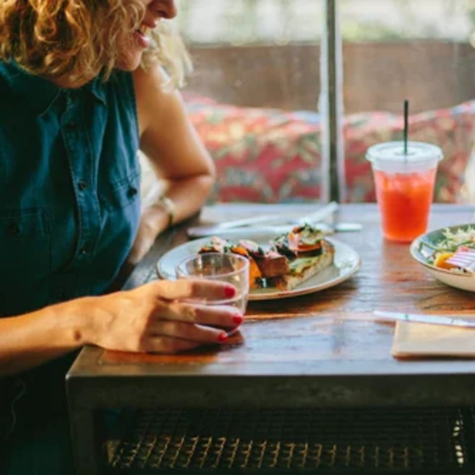 A woman enjoying a meal and drink at a table in Paper or Plastik Cafe.