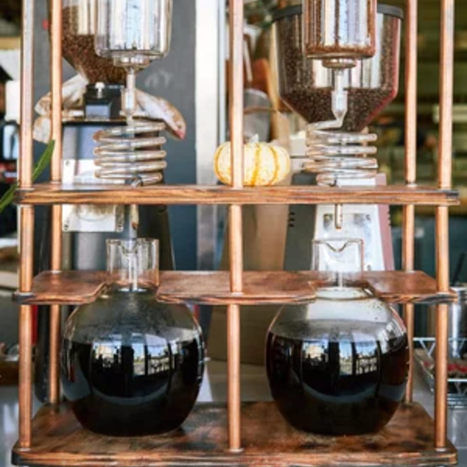 Two glass cold brew coffee makers with coffee beans and a small pumpkin decoration.