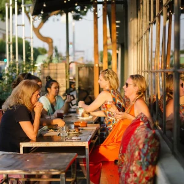 Patrons enjoying food and drinks at outdoor tables at Paper or Plastik Cafe.