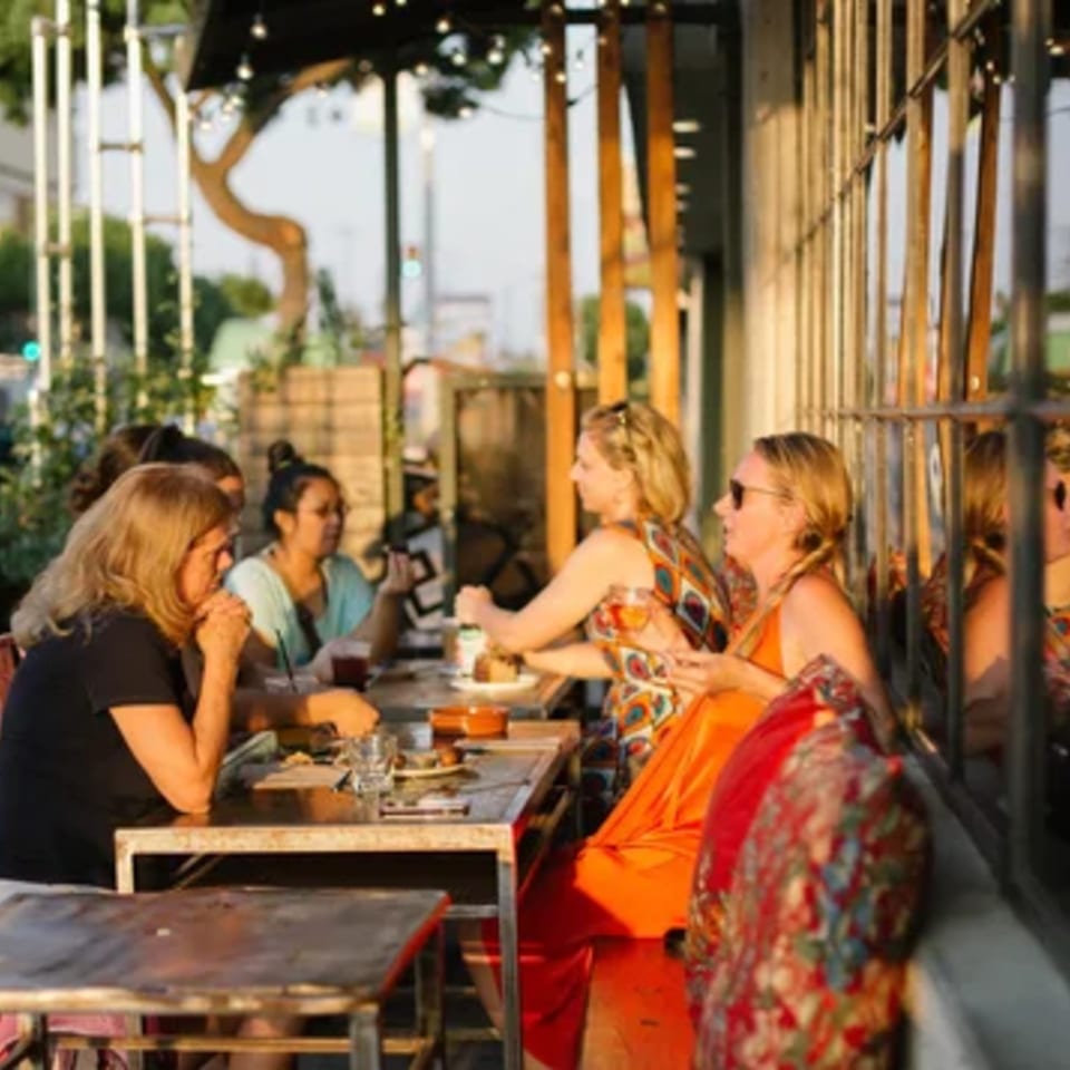 Patrons enjoying food and drinks at outdoor tables at Paper or Plastik Cafe.