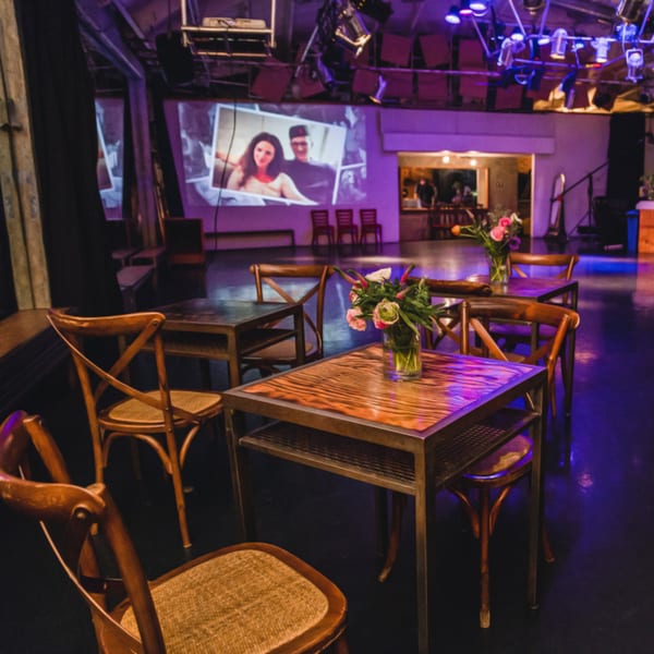 Cafe interior with wooden tables and chairs, flowers, and a projected image on the wall.