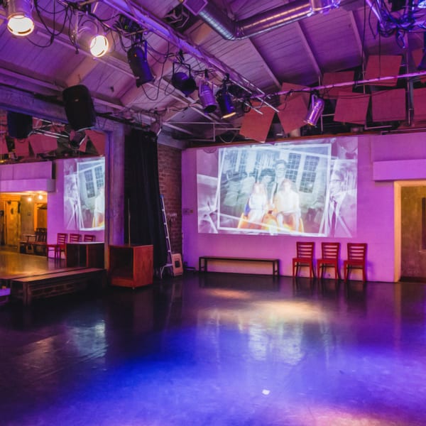 An event space with purple lighting, a large projected image, and red chairs.